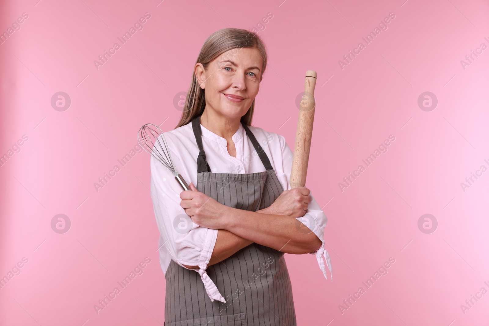 Photo of Woman with rolling pin and whisk on pink background