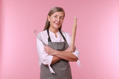 Photo of Woman with rolling pin and whisk on pink background