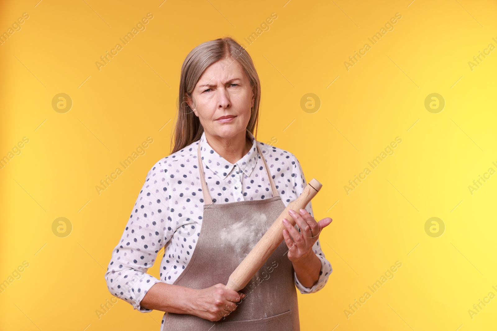 Photo of Woman with rolling pin on yellow background