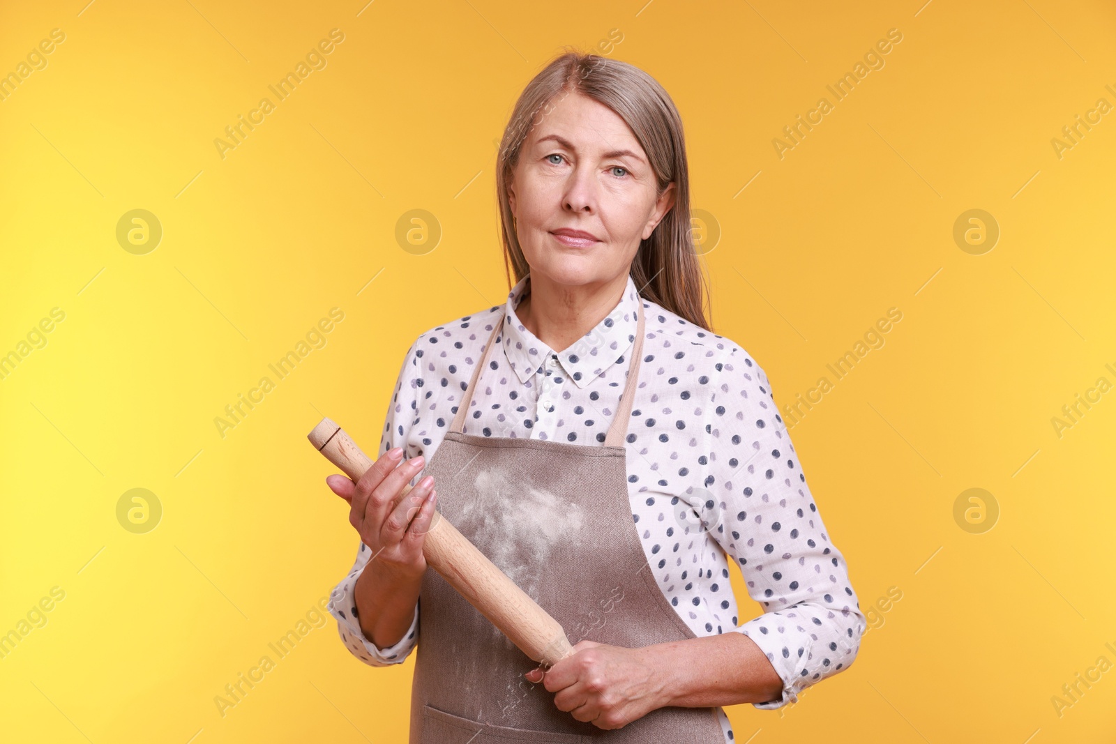 Photo of Woman with rolling pin on yellow background