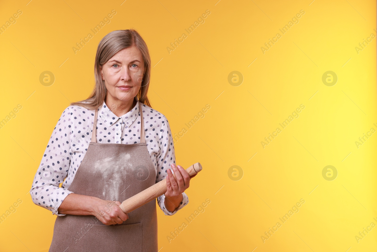 Photo of Woman with rolling pin on yellow background. Space for text