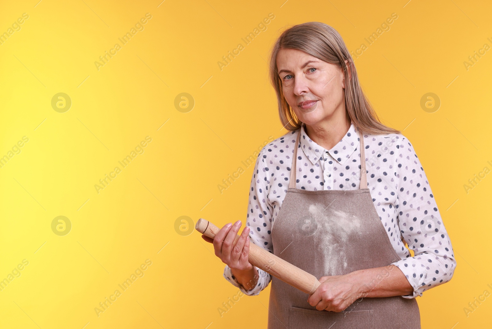 Photo of Woman with rolling pin on yellow background. Space for text