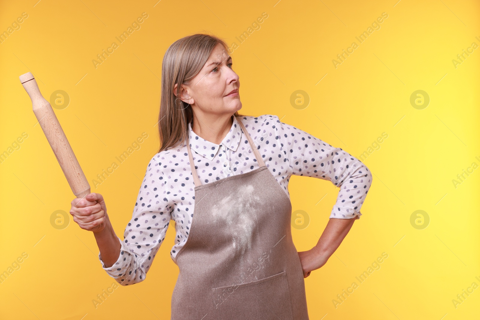 Photo of Woman with rolling pin on yellow background