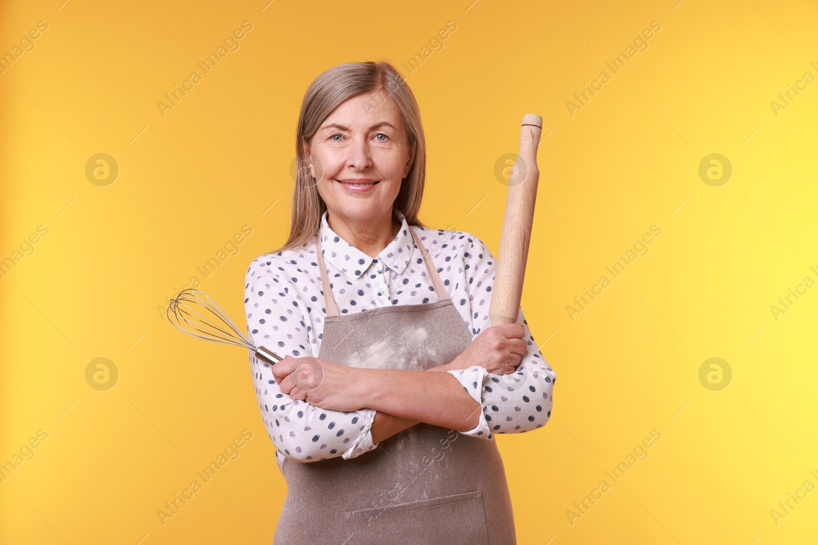 Photo of Woman with rolling pin and whisk on yellow background