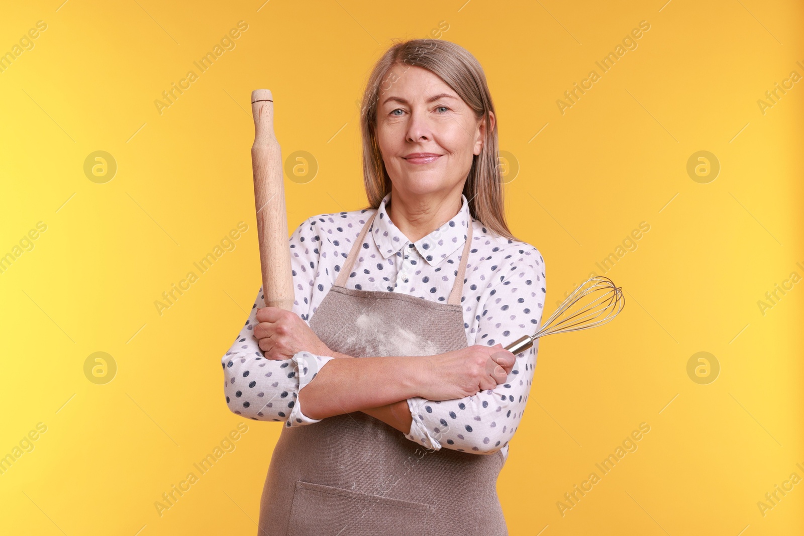 Photo of Woman with rolling pin and whisk on yellow background