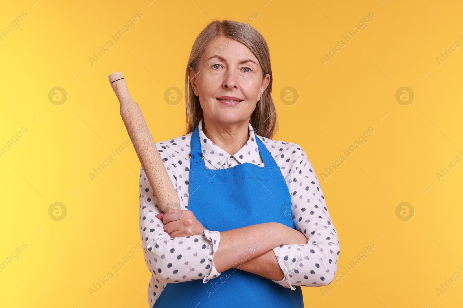 Photo of Happy woman with rolling pin on yellow background