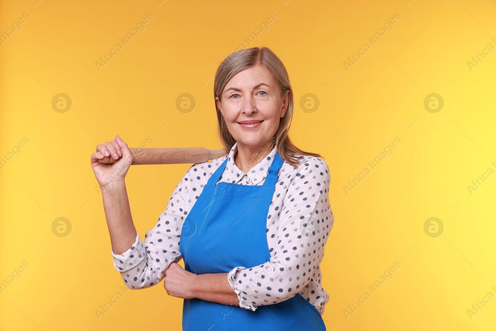 Photo of Happy woman with rolling pin on yellow background