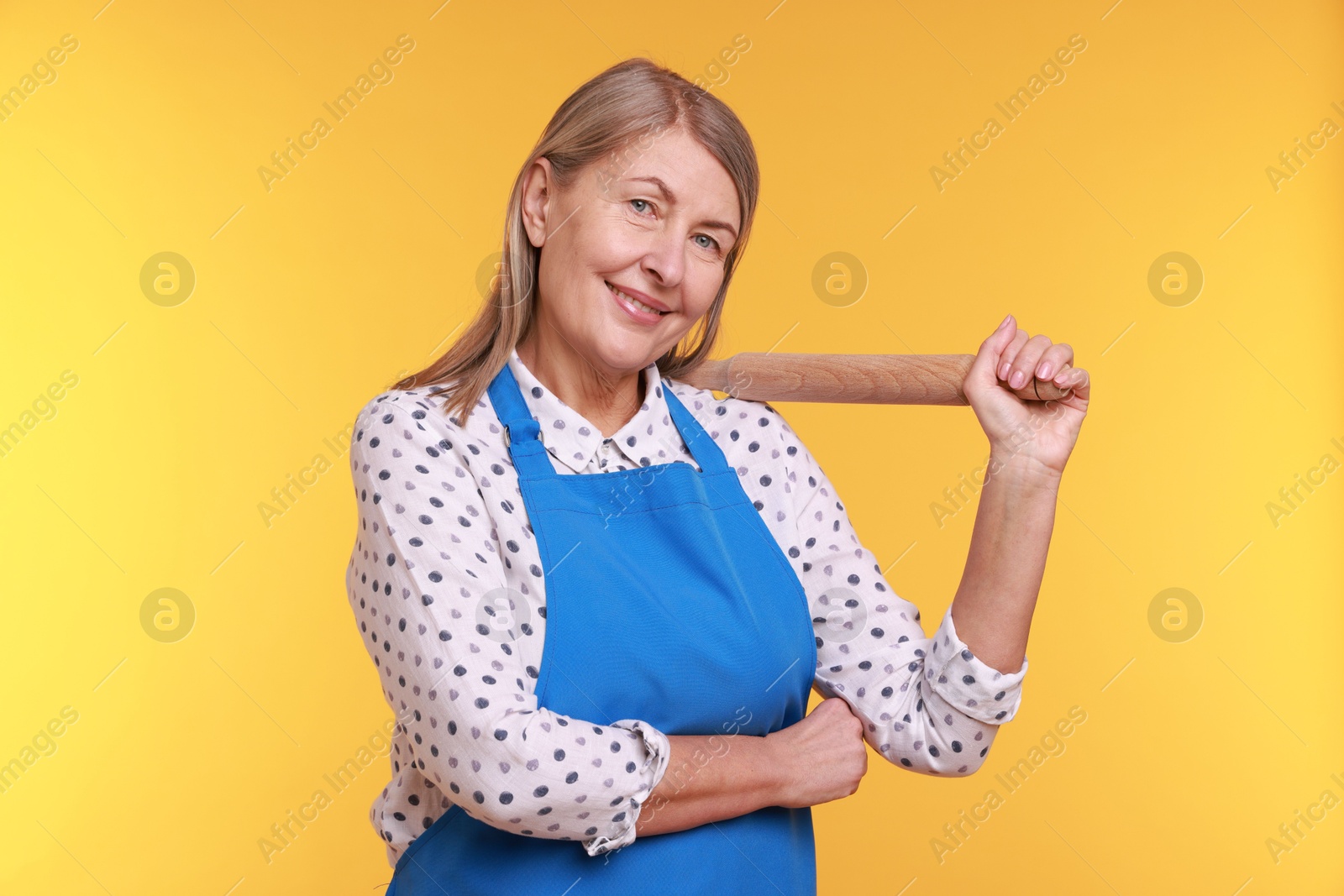 Photo of Happy woman with rolling pin on yellow background