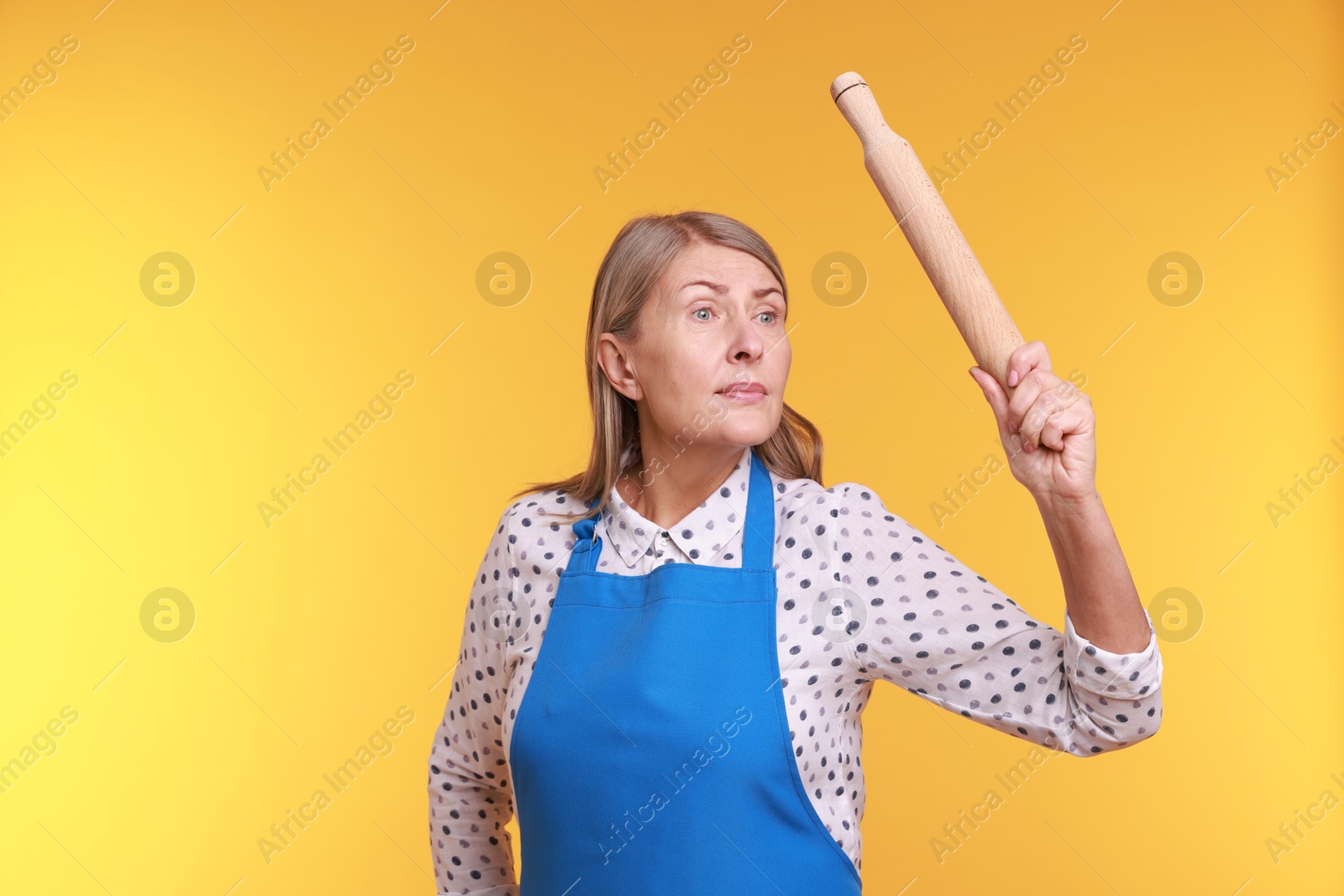 Photo of Woman with rolling pin on yellow background. Space for text