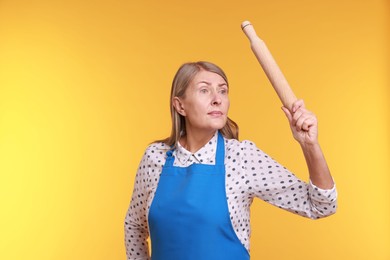 Photo of Woman with rolling pin on yellow background. Space for text