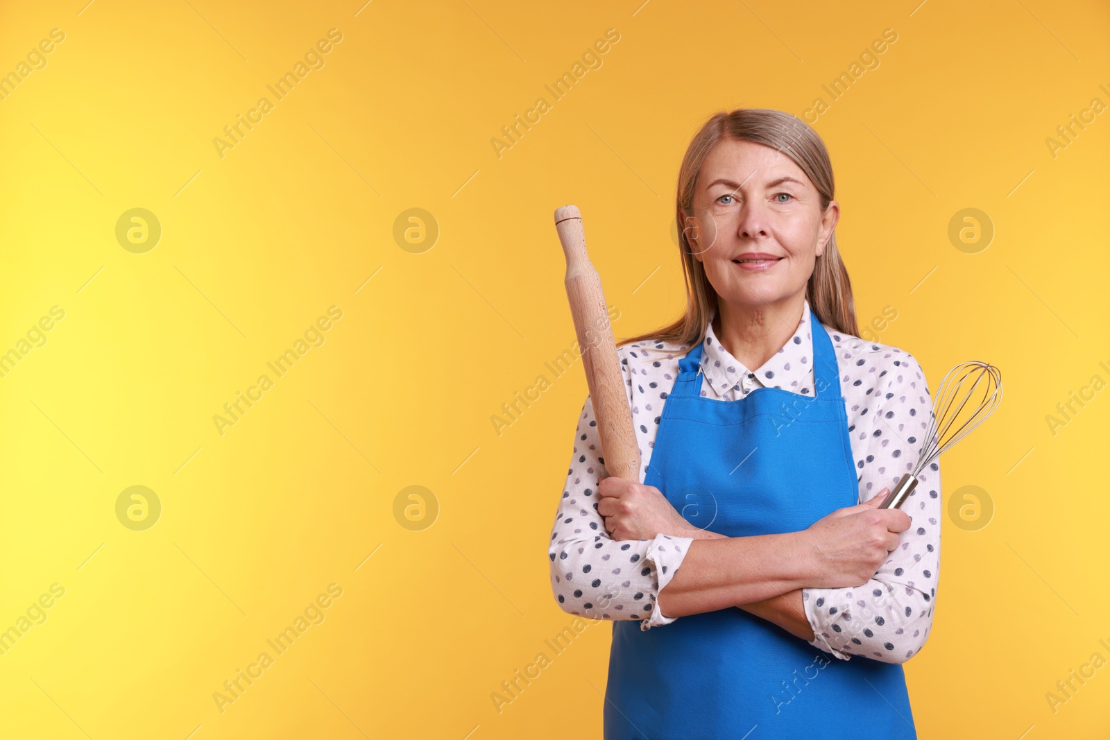 Photo of Woman with rolling pin and whisk on yellow background. Space for text