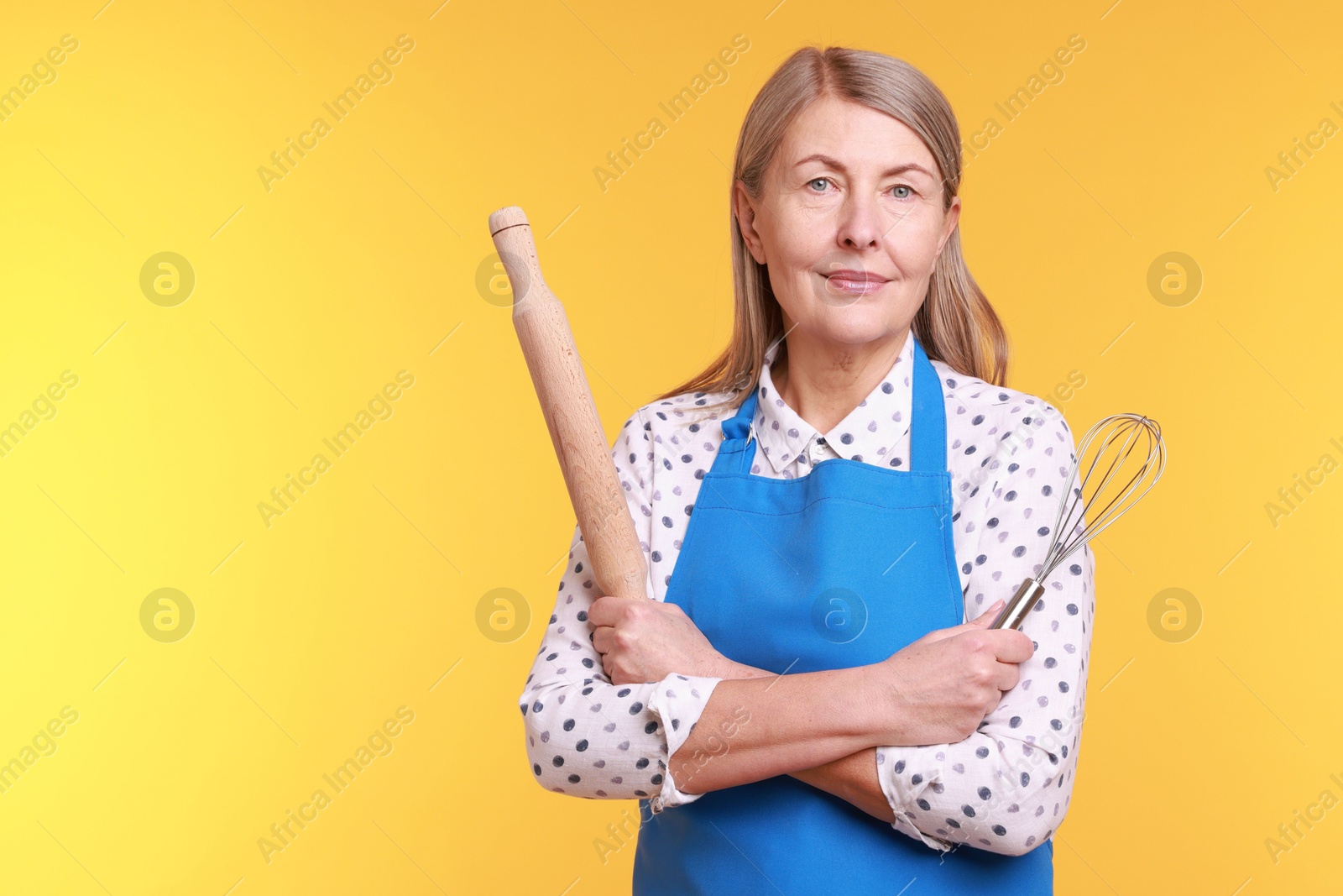 Photo of Woman with rolling pin and whisk on yellow background. Space for text