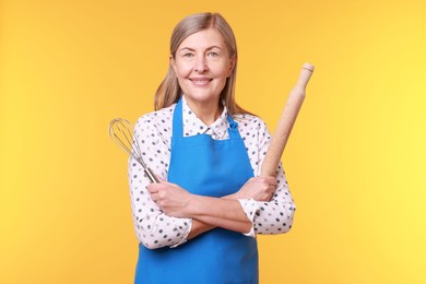 Photo of Happy woman with rolling pin and whisk on yellow background