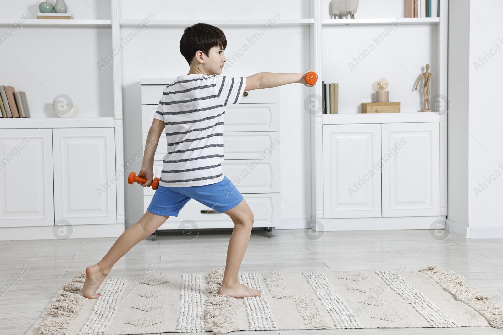 Photo of Little boy exercising with dumbbells at home. Morning routine