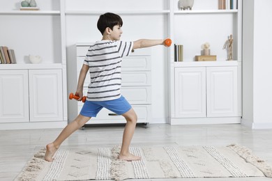 Photo of Little boy exercising with dumbbells at home. Morning routine