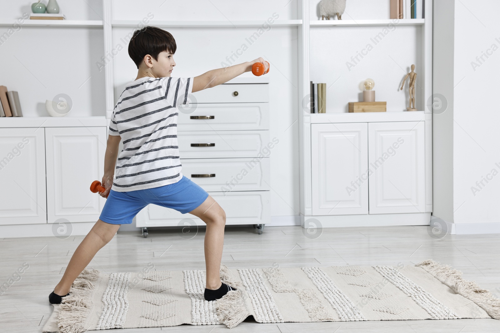 Photo of Little boy exercising with dumbbells at home. Morning routine