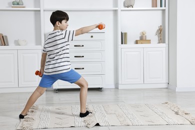 Photo of Little boy exercising with dumbbells at home. Morning routine