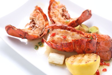 Photo of Delicious lobster tails with lemon and green onion on white table, closeup