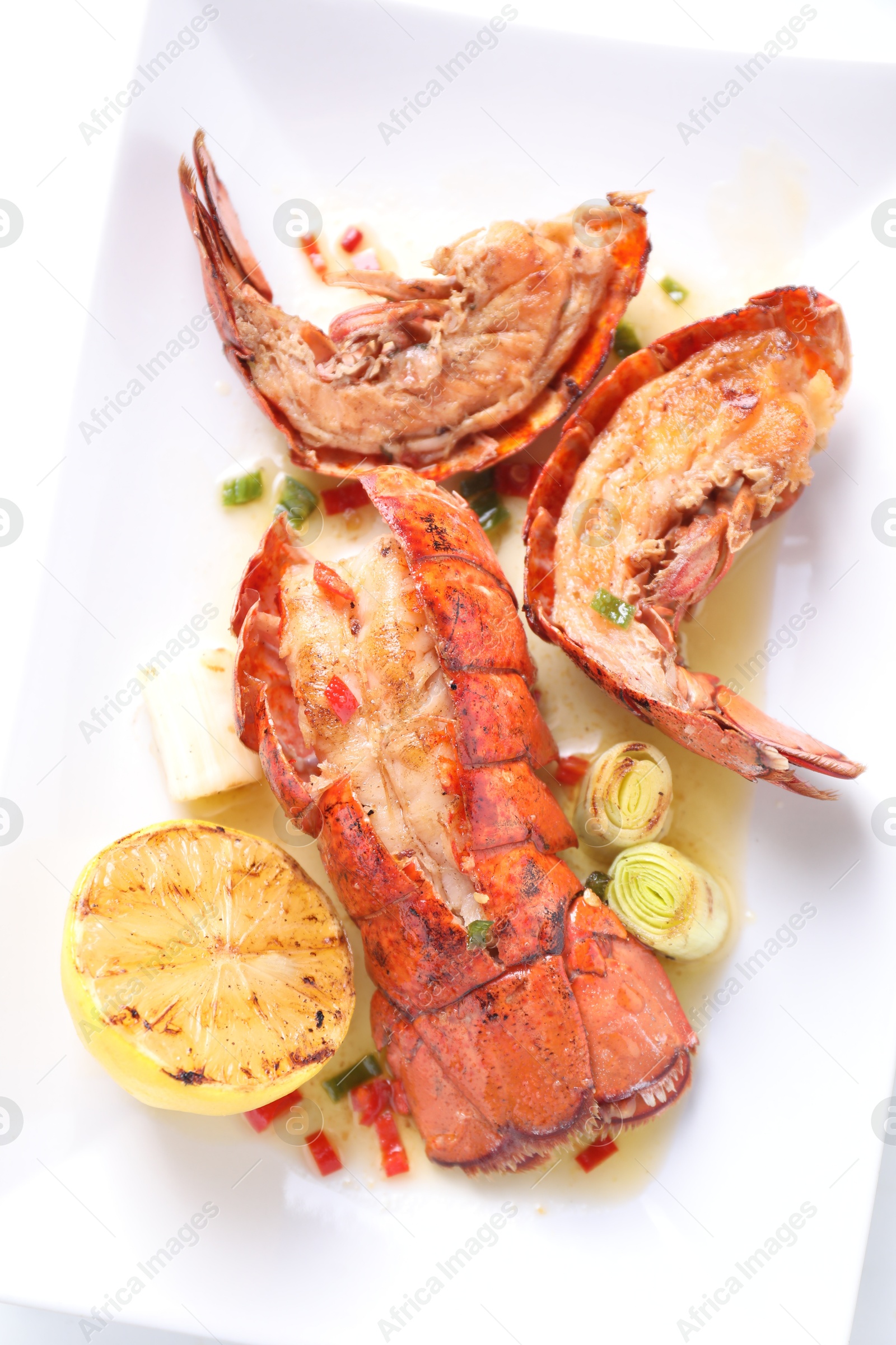 Photo of Delicious lobster tails with lemon and green onion on white table, top view