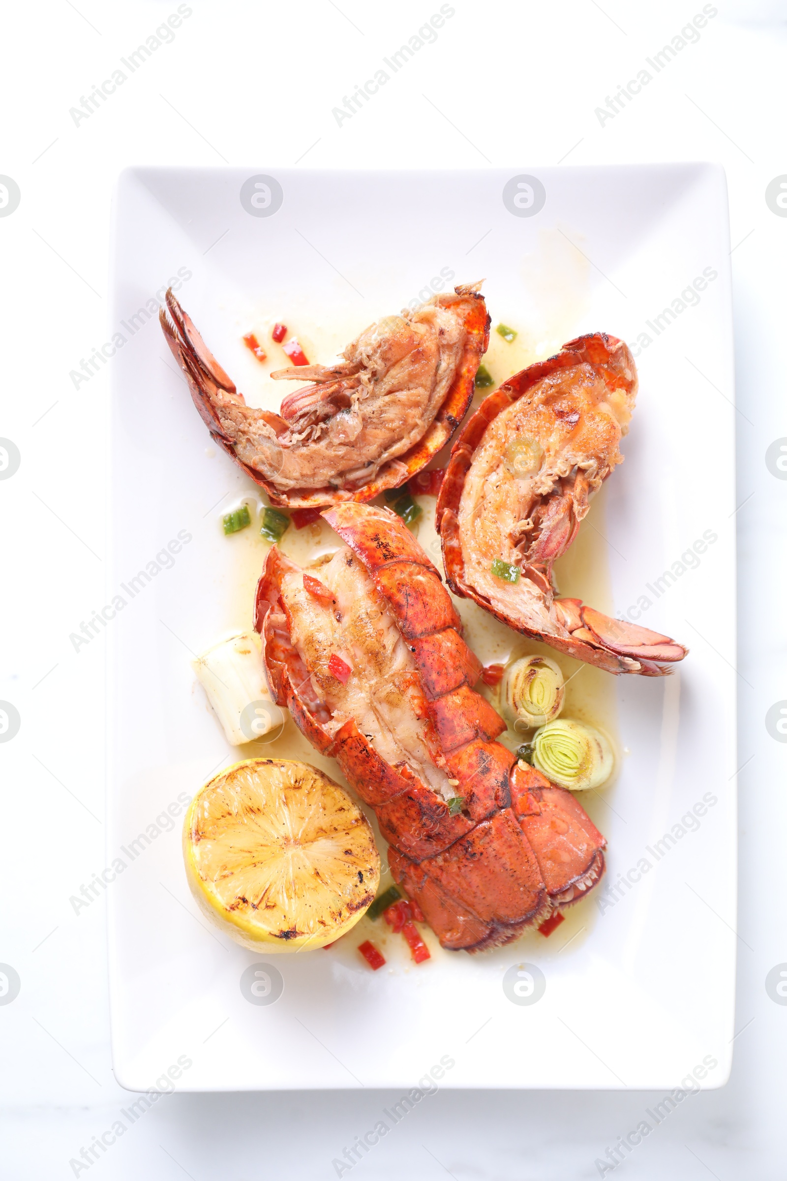 Photo of Delicious lobster tails with lemon and green onion on white table, top view