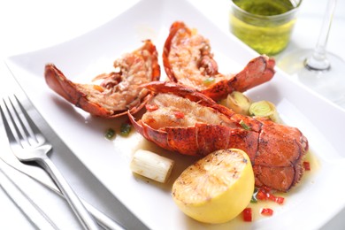 Delicious lobster tails with lemon and green onion on white table, closeup