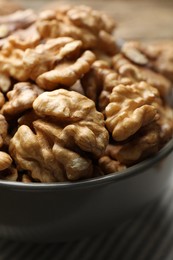 Photo of Fresh walnuts in bowl on table, closeup