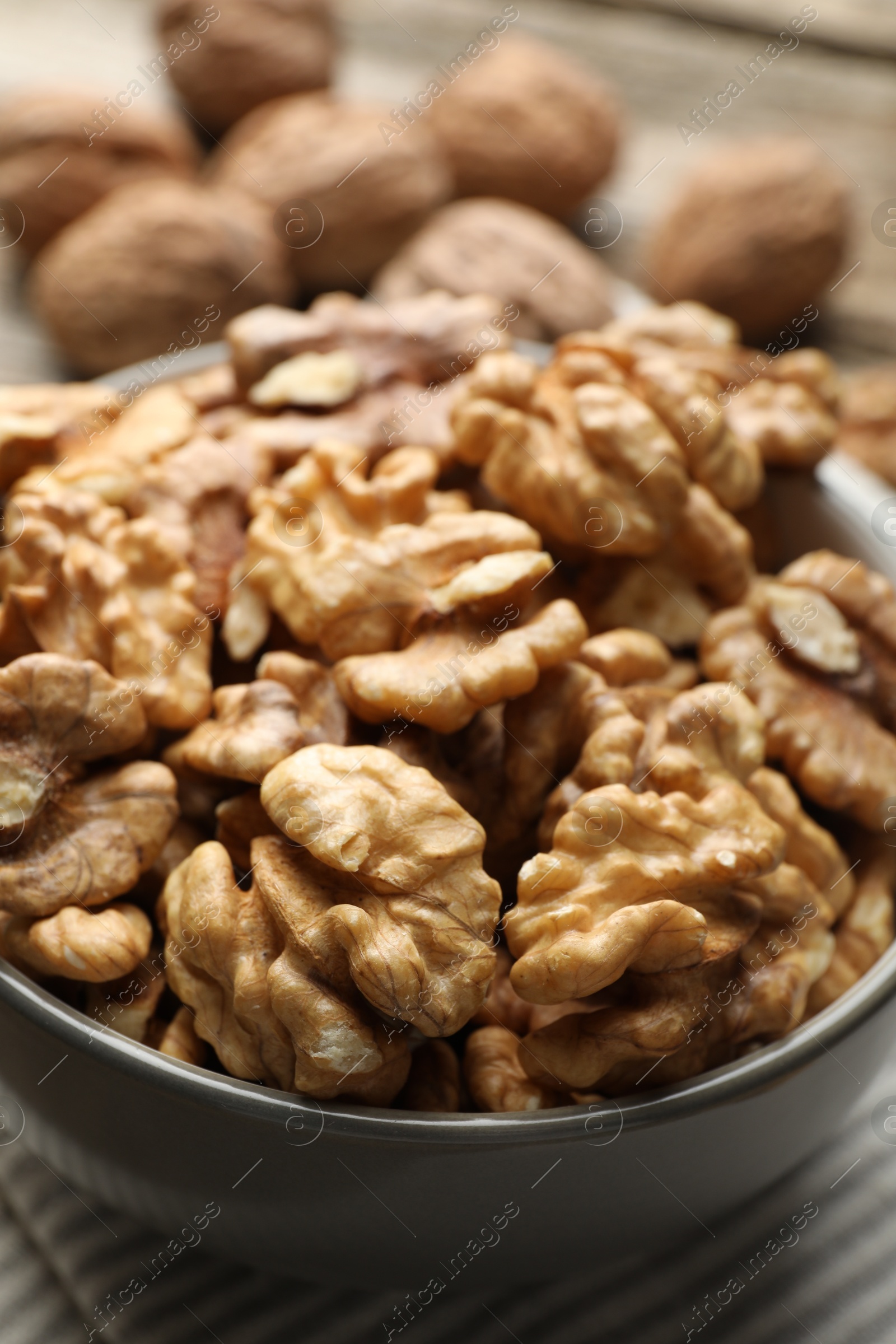 Photo of Fresh walnuts in bowl on table, closeup