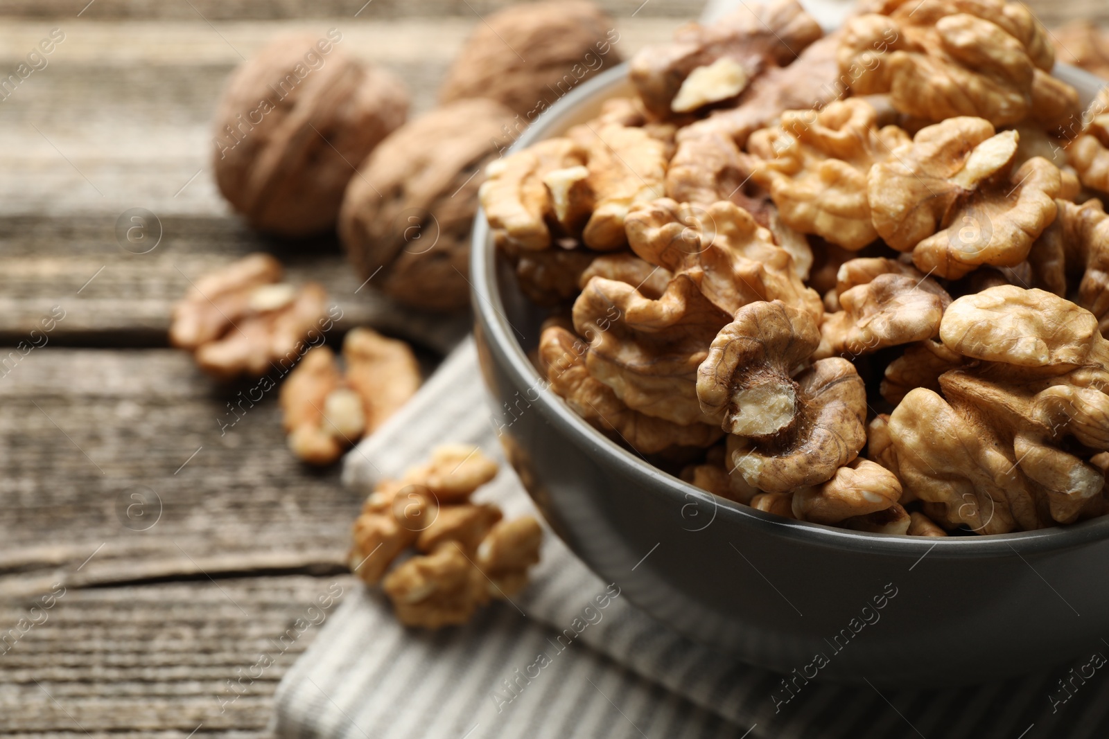 Photo of Fresh walnuts in bowl on wooden table, closeup. Space for text