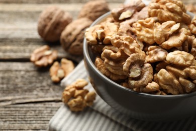 Photo of Fresh walnuts in bowl on wooden table, closeup. Space for text