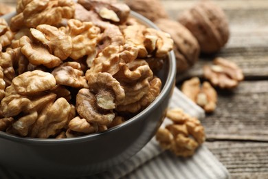 Photo of Fresh walnuts in bowl on wooden table, closeup