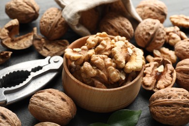 Photo of Fresh ripe walnuts, shells and nutcracker on table, closeup