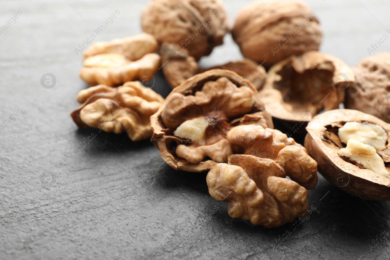 Photo of Fresh ripe walnuts and shells on black table, closeup. Space for text