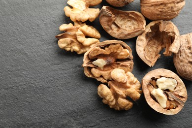 Photo of Fresh ripe walnuts and shells on black table, above view. Space for text