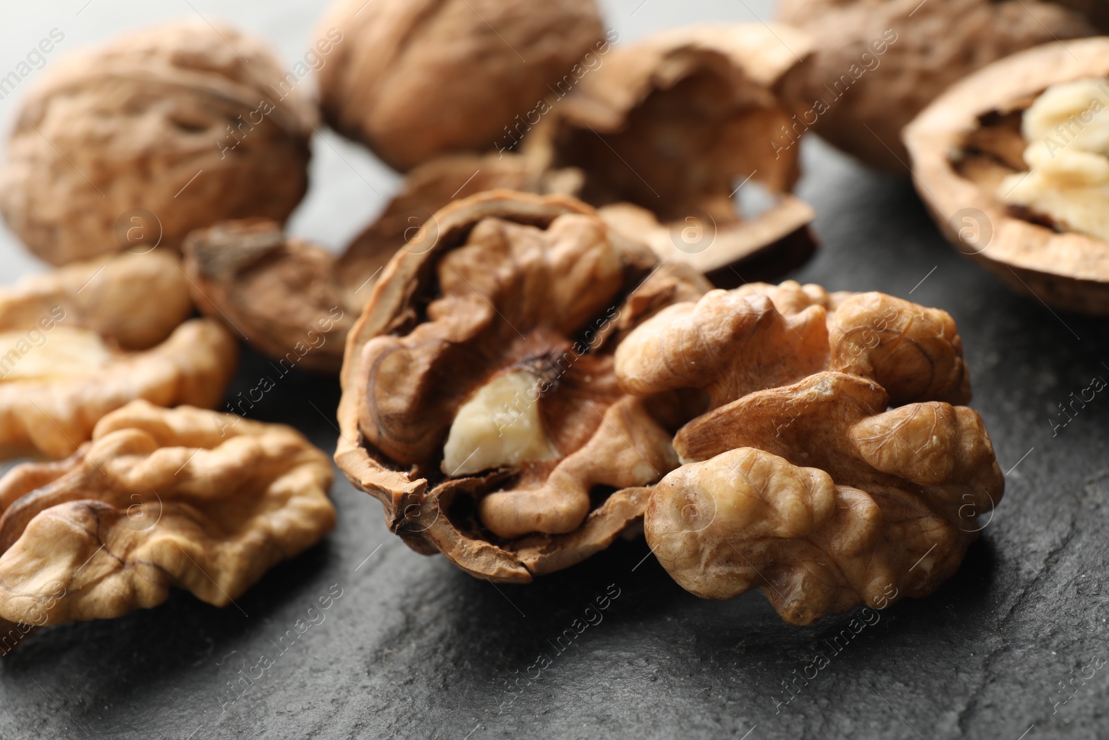 Photo of Fresh ripe walnuts and shells on black table, closeup