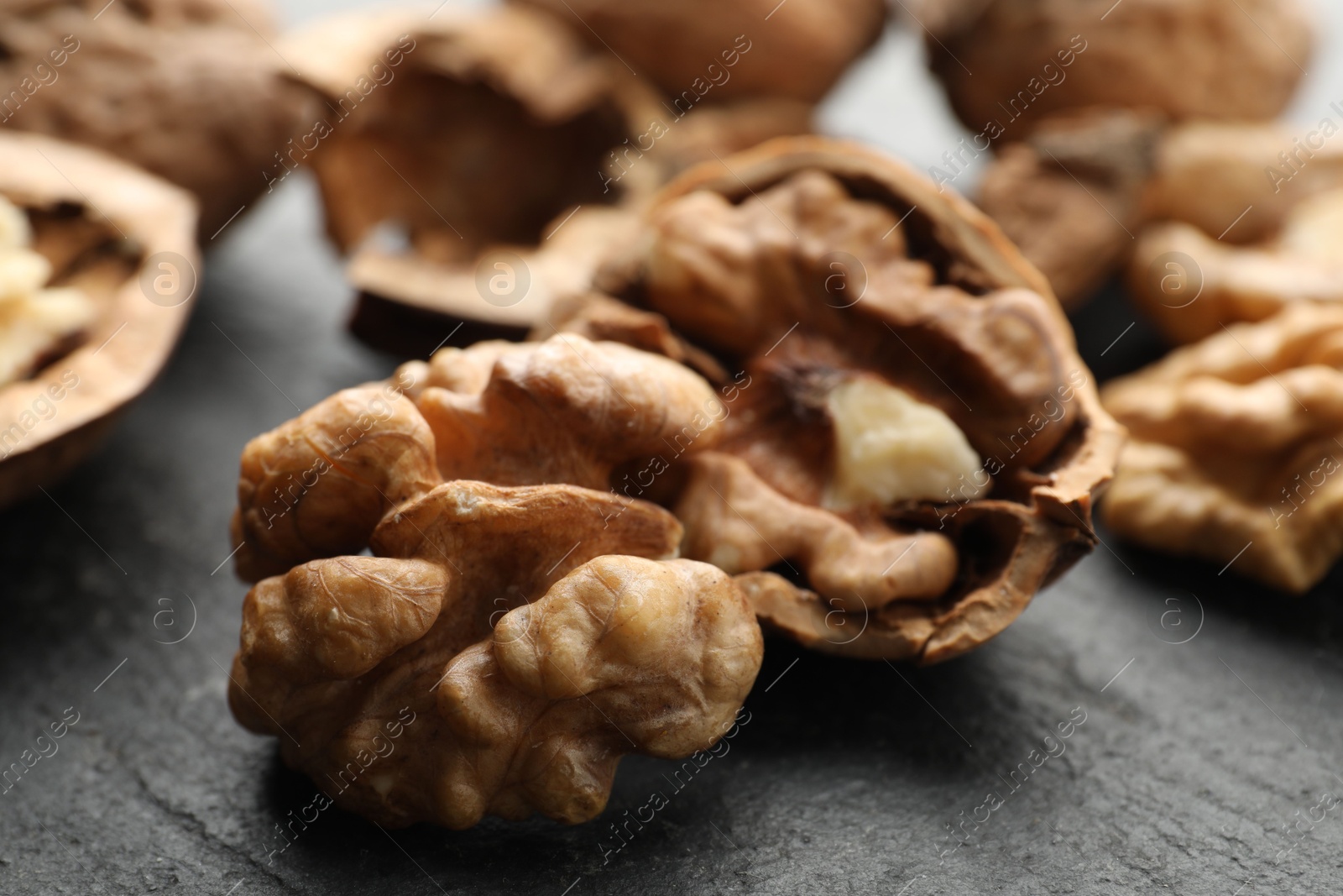 Photo of Fresh ripe walnuts and shells on black table, closeup