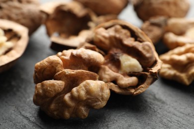 Photo of Fresh ripe walnuts and shells on black table, closeup