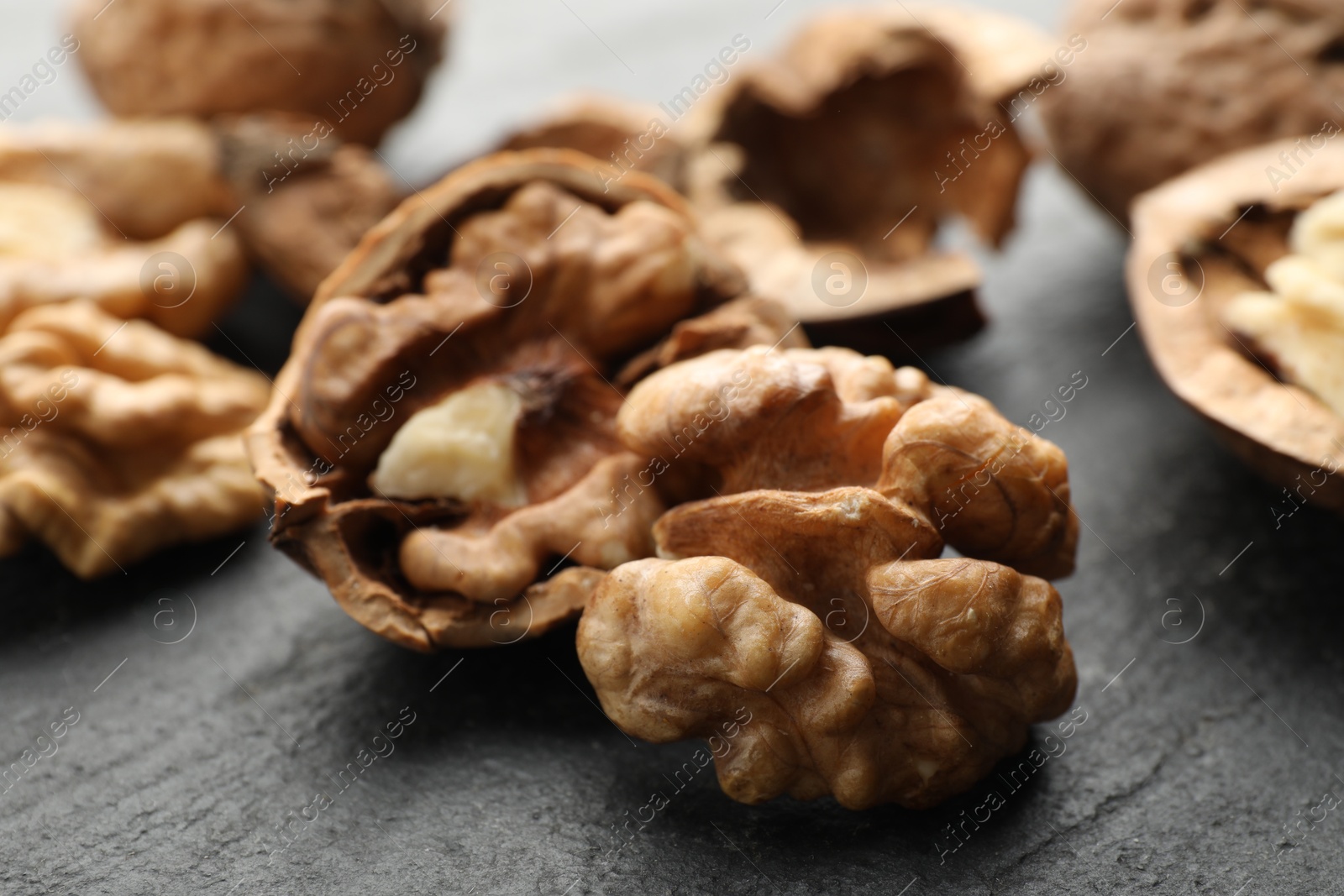 Photo of Fresh ripe walnuts and shells on black table, closeup