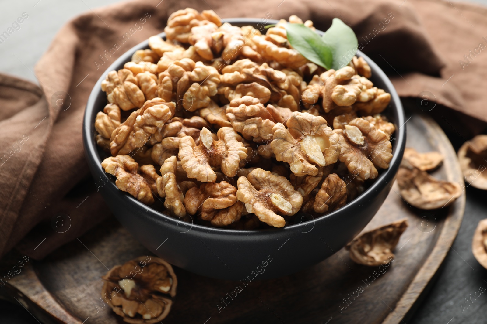 Photo of Fresh ripe walnuts in bowl on table, closeup