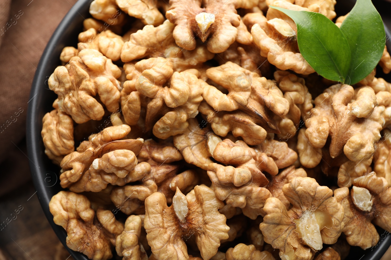 Photo of Fresh ripe walnuts in bowl on table, top view