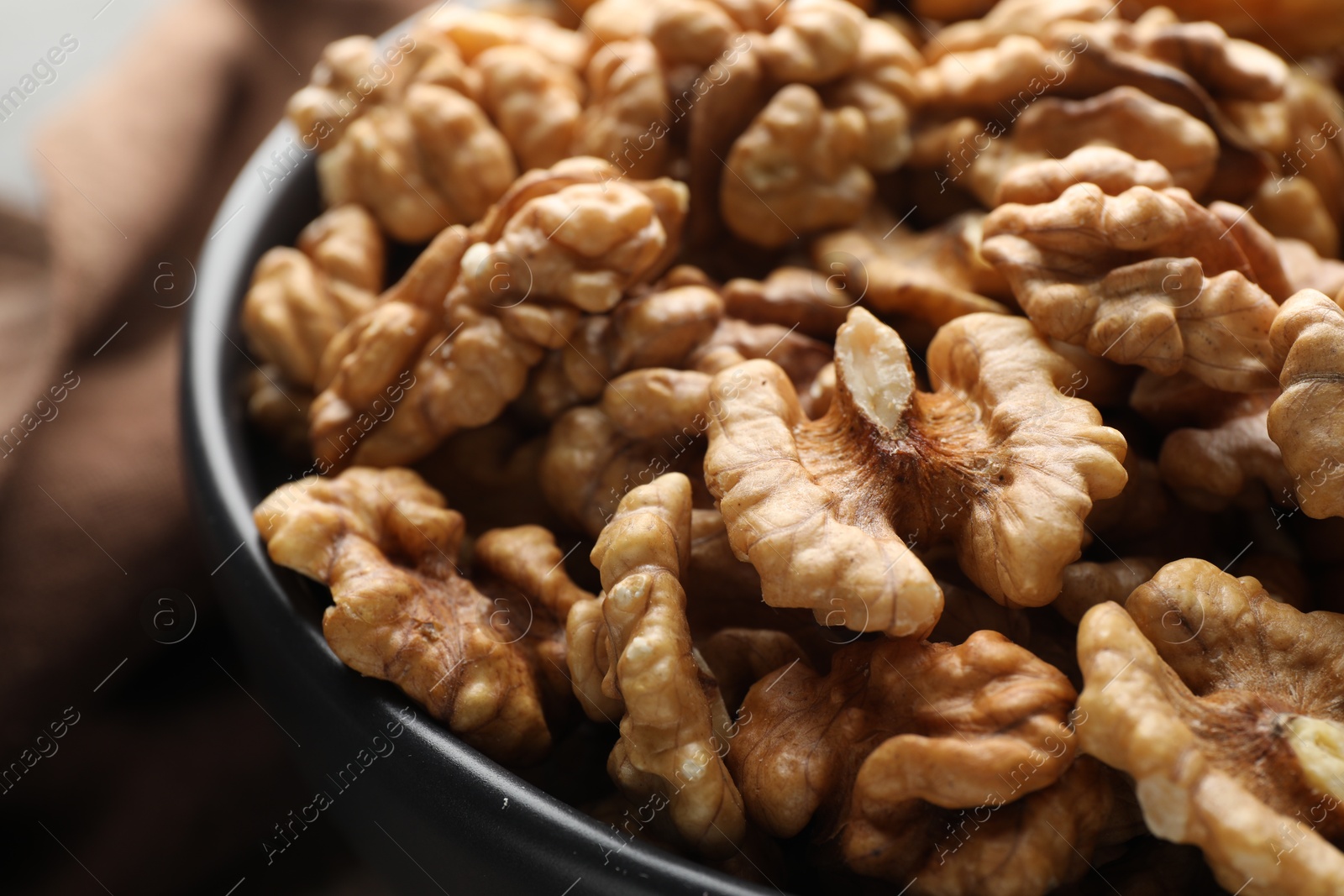 Photo of Fresh ripe walnuts in bowl on table, closeup