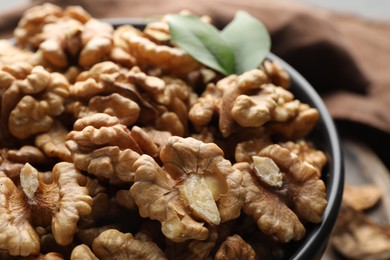 Photo of Fresh ripe walnuts in bowl on table, closeup