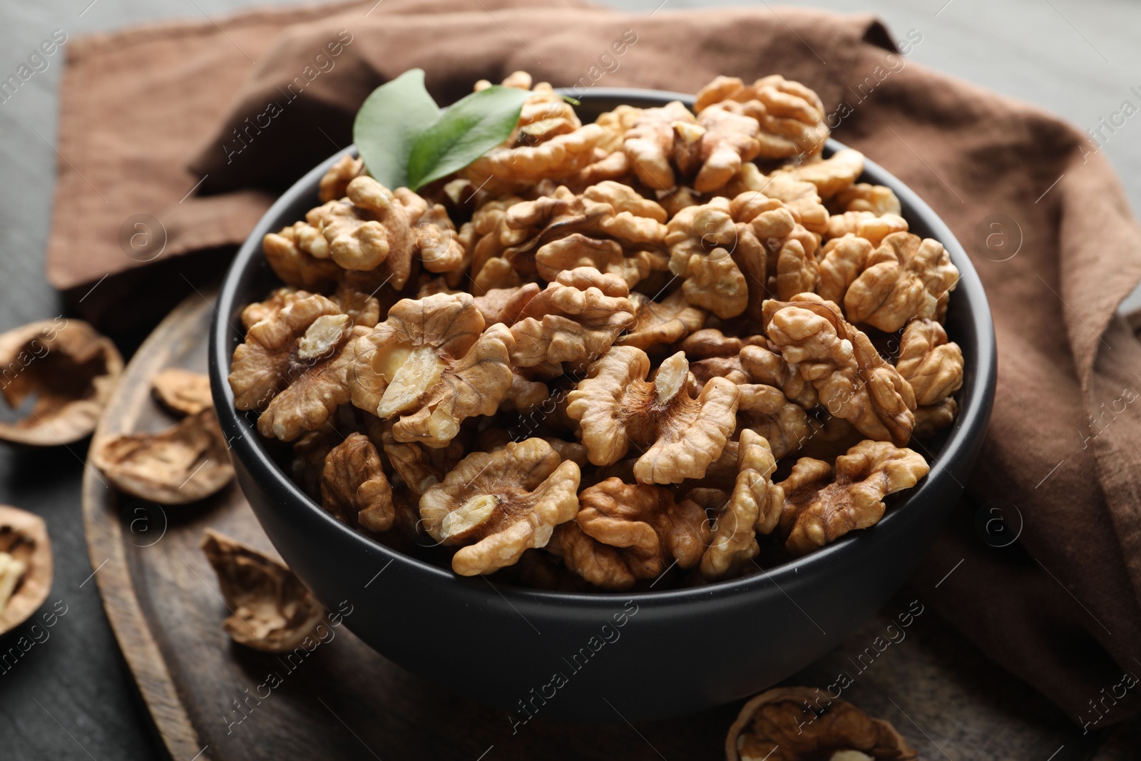 Photo of Fresh ripe walnuts in bowl on table, closeup