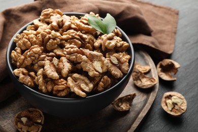 Photo of Fresh ripe walnuts in bowl on black table, closeup