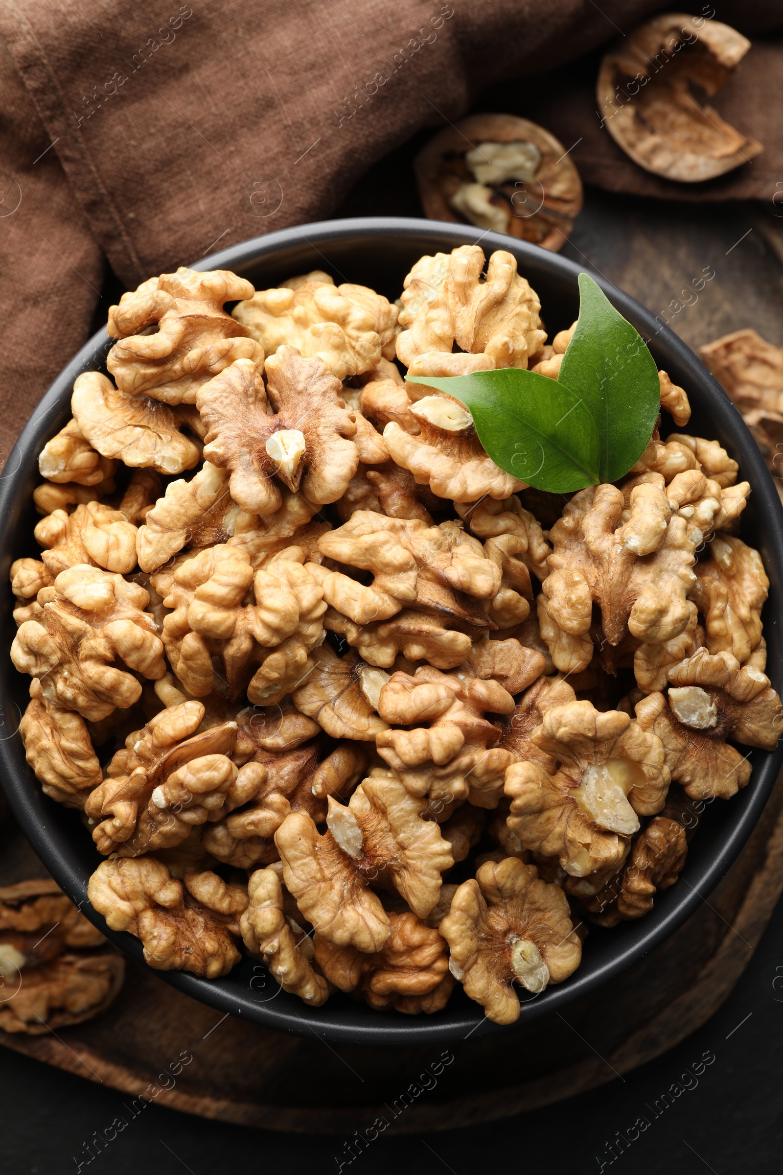 Photo of Fresh ripe walnuts in bowl on table, top view