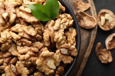 Photo of Fresh ripe walnuts in bowl and shells on table, top view