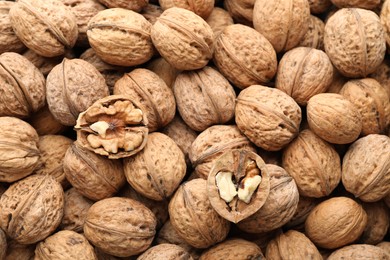 Photo of Fresh walnuts in shells as background, top view