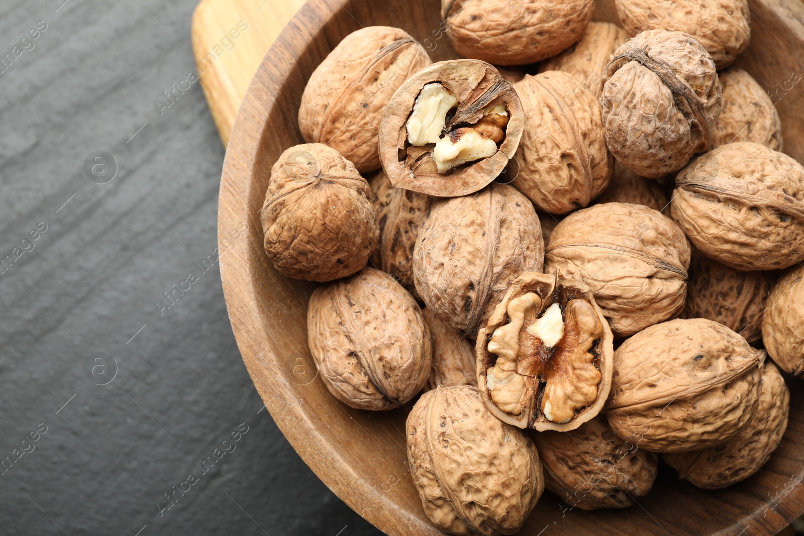 Photo of Fresh walnuts in shells on black table, top view. Space for text