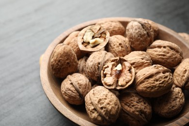 Photo of Fresh ripe walnuts in shells on black table, closeup