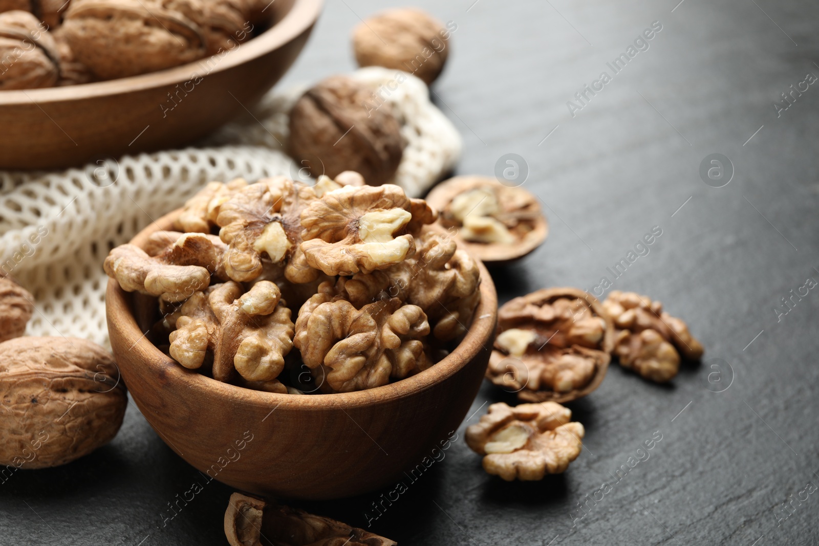 Photo of Fresh ripe walnuts and shells on black table, closeup. Space for text