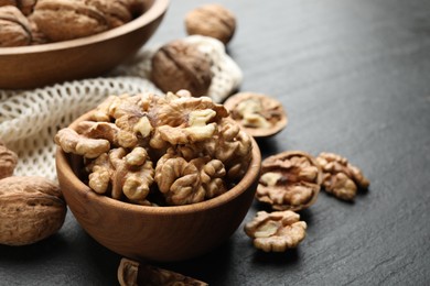 Photo of Fresh ripe walnuts and shells on black table, closeup. Space for text